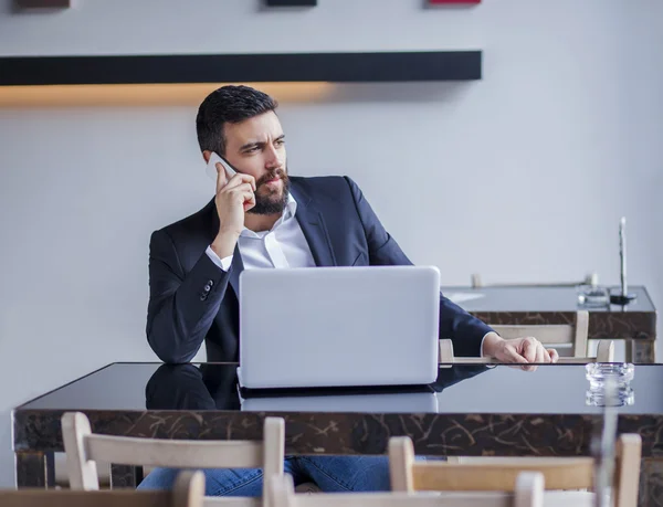 Businessman talking on phone in restaurant — Stock Photo, Image