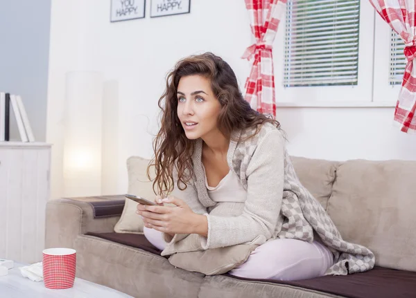 Mujer en sofá sosteniendo teléfono —  Fotos de Stock