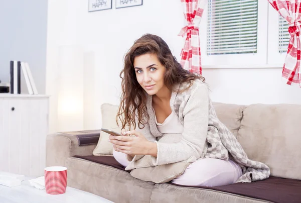 Mujer en sofá sosteniendo teléfono — Foto de Stock