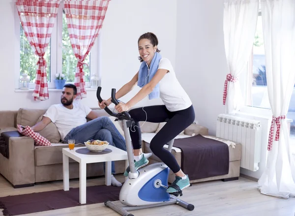 Entrenamiento de mujer en bicicleta estática en la habitación — Foto de Stock