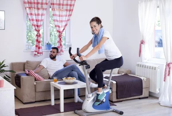 Woman training on exercise bike in room — Stock Photo, Image