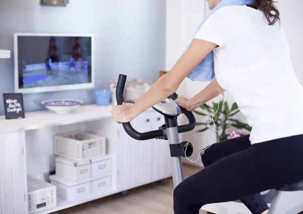 Mulher formação em bicicleta de exercício no quarto — Fotografia de Stock