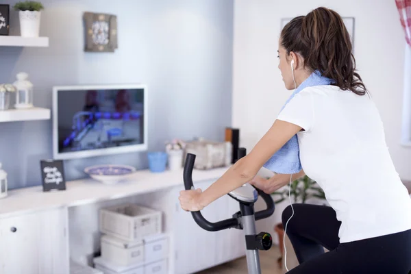 Woman training on exercise bike in room — Stock Photo, Image