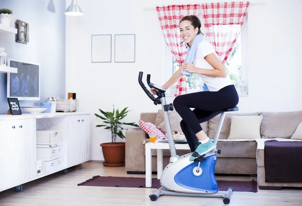 Mulher formação em bicicleta de exercício no quarto — Fotografia de Stock
