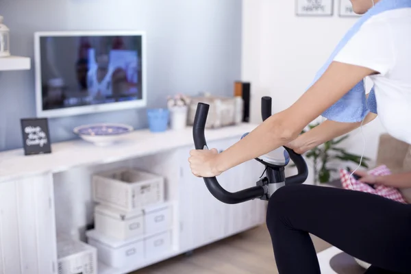 Woman training on exercise bike in room — Stock Photo, Image