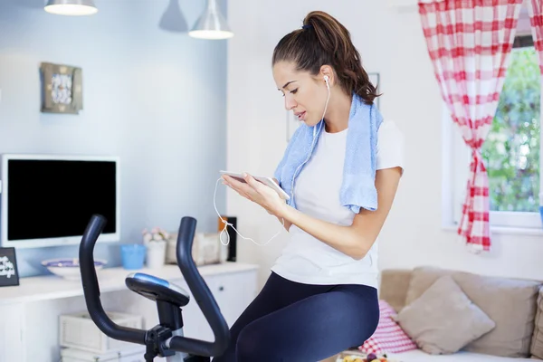 Entrenamiento de mujer en bicicleta estática usando tableta — Foto de Stock