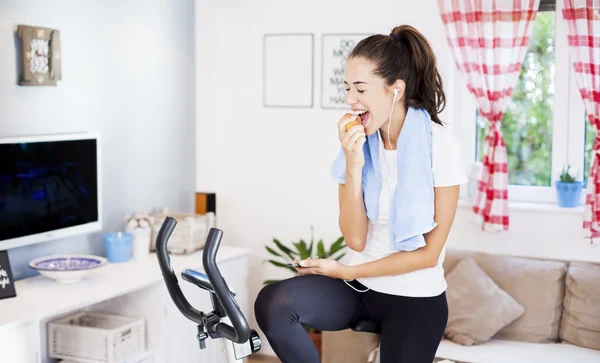 Mujer comiendo manzana mientras entrena en casa — Foto de Stock