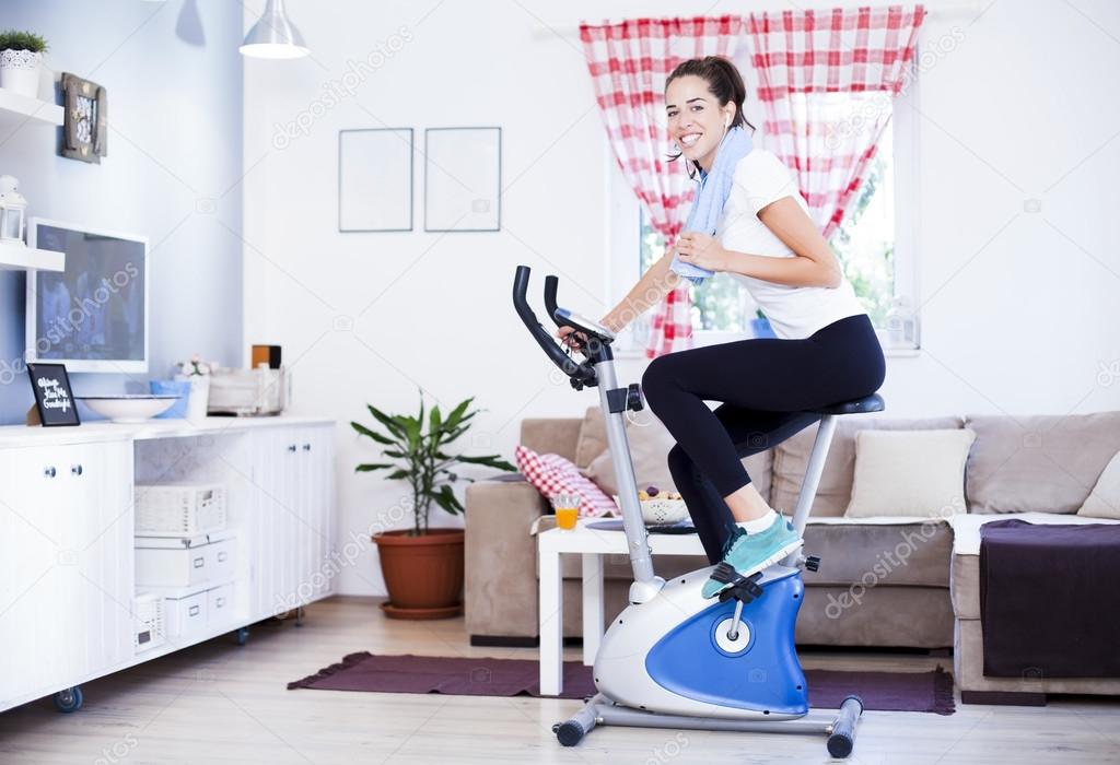 woman training on exercise bike in room