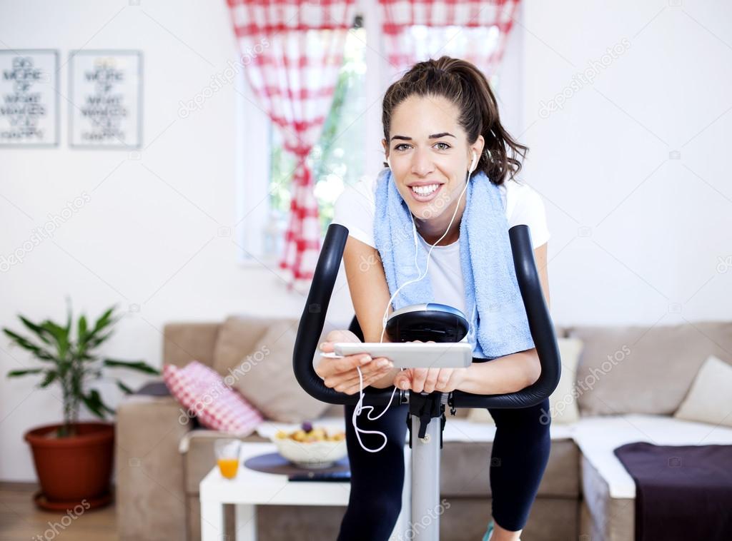woman training on exercise bike using tablet