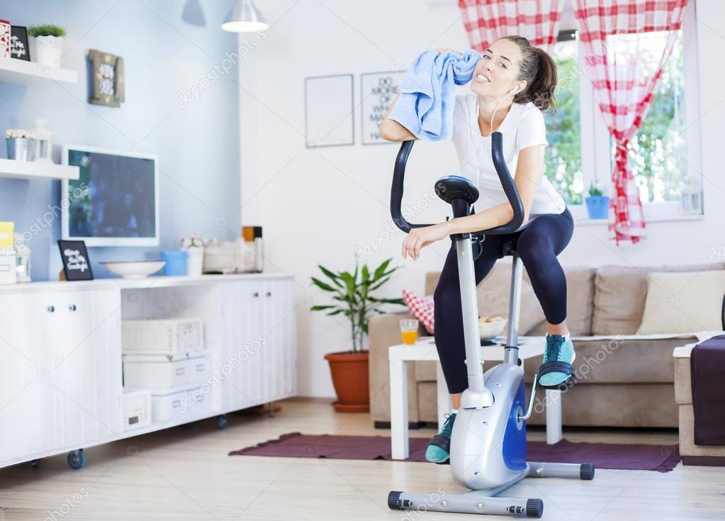woman training on exercise bike in room