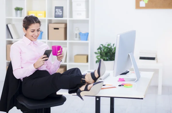 Mujer de negocios con piernas en el escritorio — Foto de Stock