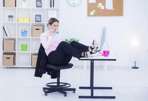 Mujer de negocios con piernas en el escritorio de telefonía — Foto de Stock