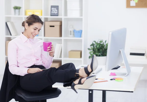 Mujer de negocios con piernas en el escritorio —  Fotos de Stock