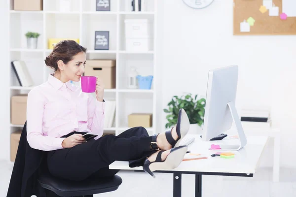 Mujer de negocios con piernas en el escritorio — Foto de Stock