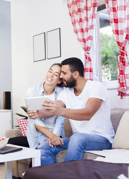 Casal usando tablet no sofá — Fotografia de Stock