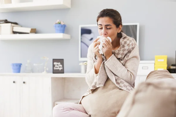 Sick woman blowing nose on sofa — Stok Foto