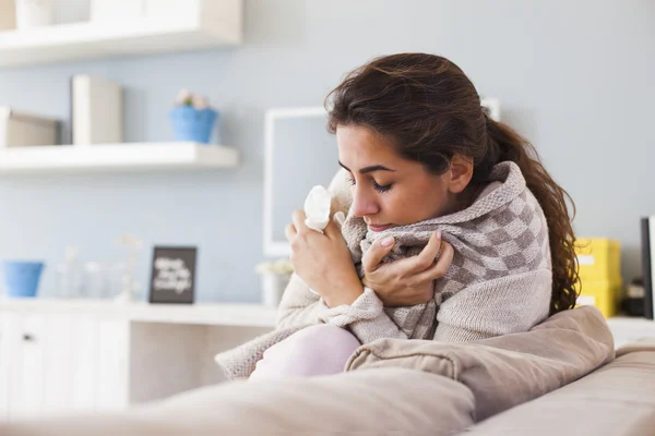 Sick woman blowing nose on sofa — Stok Foto