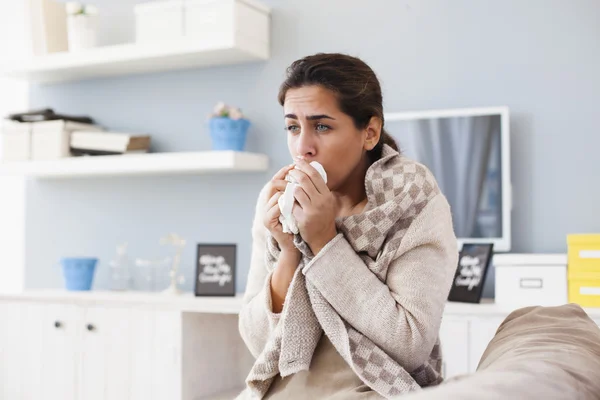 Sick woman blowing nose on sofa — Stok Foto