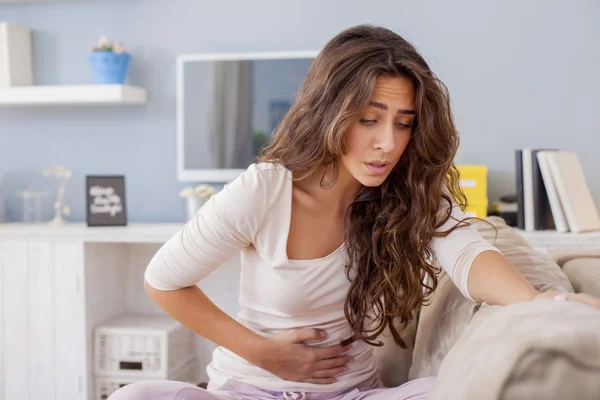 Woman on bed with stomach pain — Stock Photo, Image