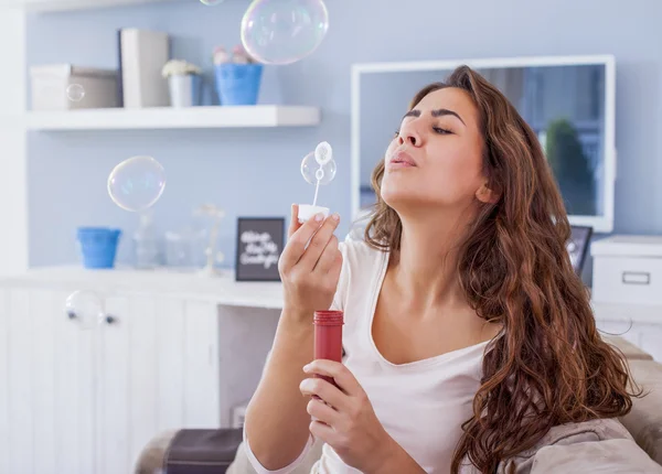 Schöne Frau bläst Blasen in ihrem Wohnzimmer und hat Spaß. geringe Schärfentiefe — Stockfoto