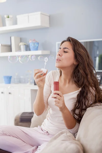 Beautiful woman blowing bubbles in her living room,having fun. Shallow depth of field — Stock Photo, Image