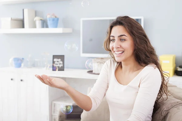 Mooie vrouw bellen blazen in haar woonkamer, plezier. Ondiepe scherptediepte — Stockfoto