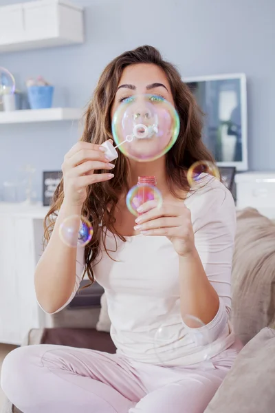 Beautiful woman blowing bubbles in her living room,having fun. Shallow depth of field — Stock Photo, Image