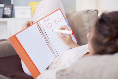 Rahat yatağında oturmuş ve notlar günlüğünü, sığ derinliği için yapım genç ve güzel kadın şikayetçi