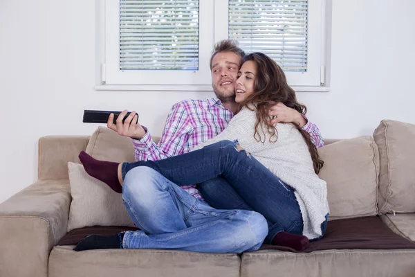 Casal atraente abraçando no sofá em casa na sala de estar — Fotografia de Stock