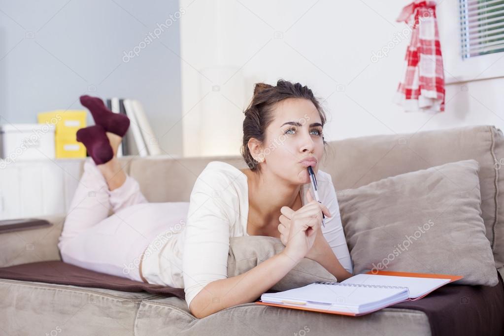Pretty young woman sitting on her cozy bed and making notes to her diary,shallow depth of filed