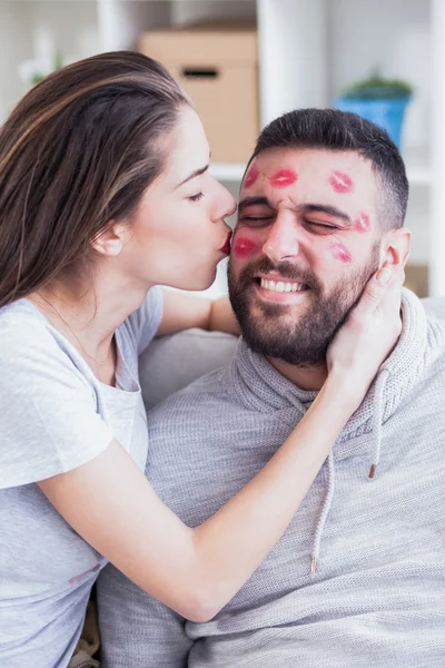 Valentines couple. Woman kissing man with red lipstick all over his face,shallow depth of field — Stock Photo, Image