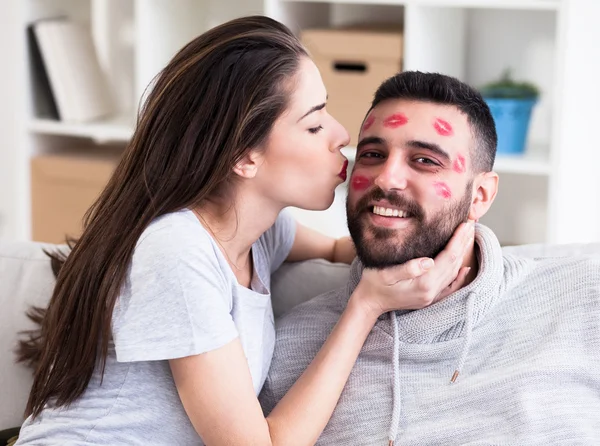 Pareja de San Valentín. Mujer besándose hombre con lápiz labial rojo por toda su cara, poca profundidad de campo — Foto de Stock