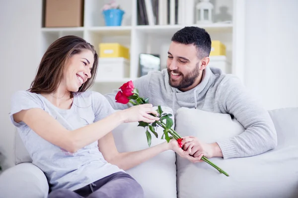 Jovem dando uma rosa vermelha para sua namorada — Fotografia de Stock