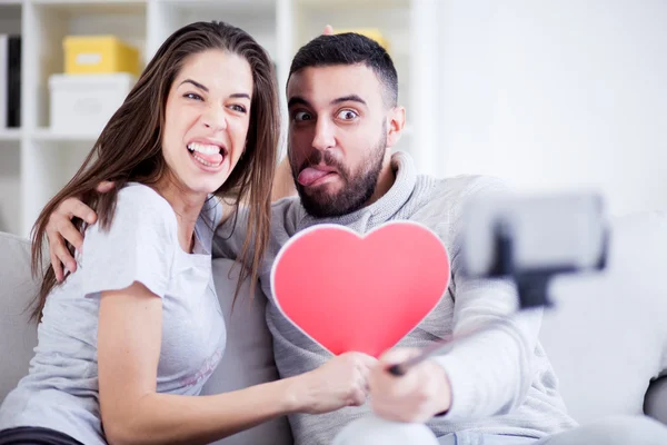 행복 한 젊은 아름 다운 커플 selfie 막대기에 스마트 폰으로 사진을 복용. 젊은 부부는 거실에 있는 재미 — 스톡 사진