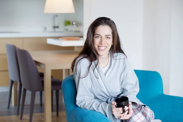 Жінка на дивані тримає каву — стокове фото