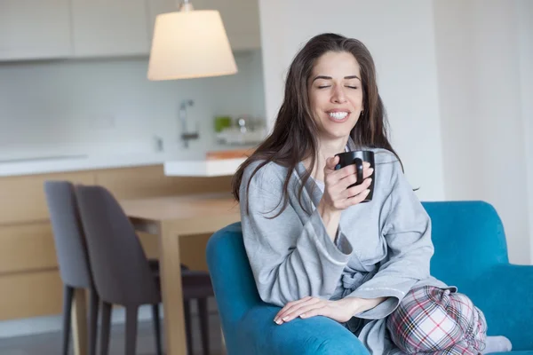 Kvinna på soffan håller kaffe — Stockfoto