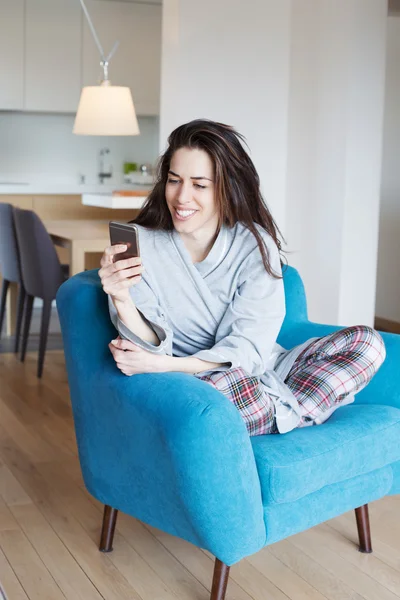 Женщина в диване и с помощью телефона — стоковое фото