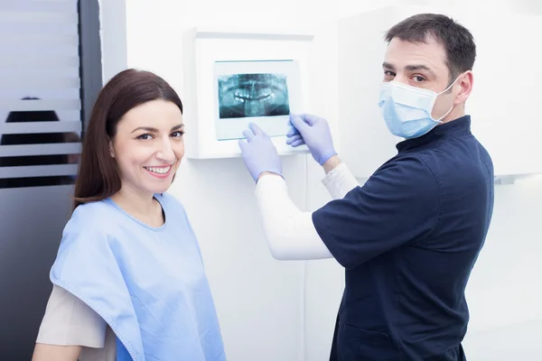 Ανδρικής οδοντίατρο δείχνει ακτινογραφία του ασθενή στην οδοντιατρική κλινική — Φωτογραφία Αρχείου
