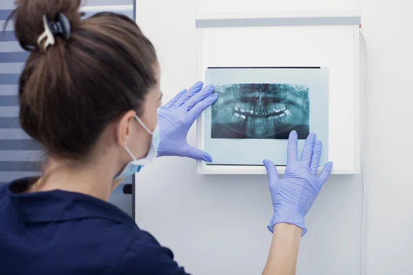 Kadın doktor, diş röntgenine bakıyor.