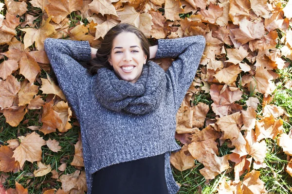 Женщина лежит над листьями и улыбается — стоковое фото
