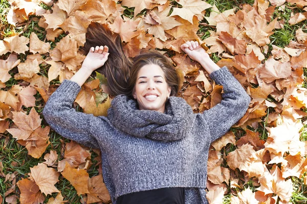 Ritratto di una donna autunnale sdraiata sulle foglie e sorridente — Foto Stock