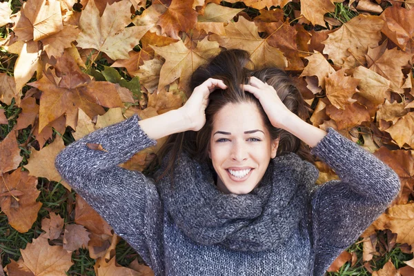 Ritratto di una donna autunnale sdraiata sulle foglie e sorridente — Foto Stock