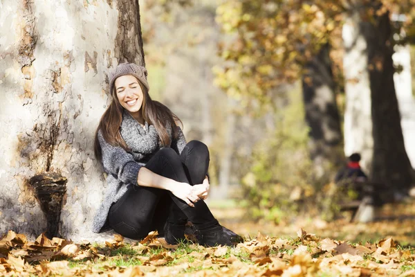 Портрет великолепной брюнетки в осеннем парке, играющей с листьями — стоковое фото
