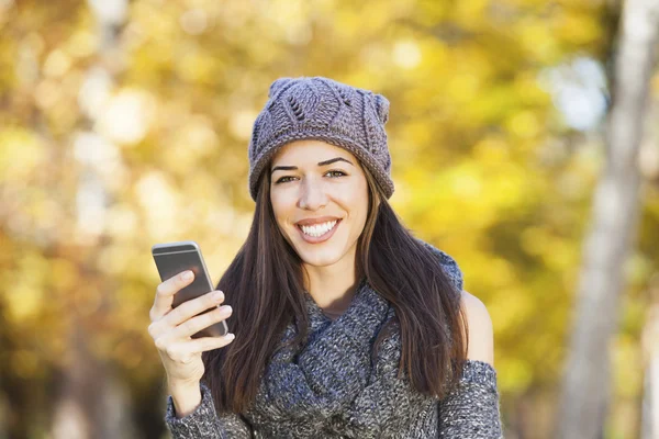 Vacker kvinna gå i höst park. Höstsäsongen. Kvinnan talar i telefon — Stockfoto