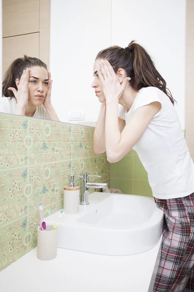 Mujer salpicando la cara con agua por encima del lavabo del baño —  Fotos de Stock