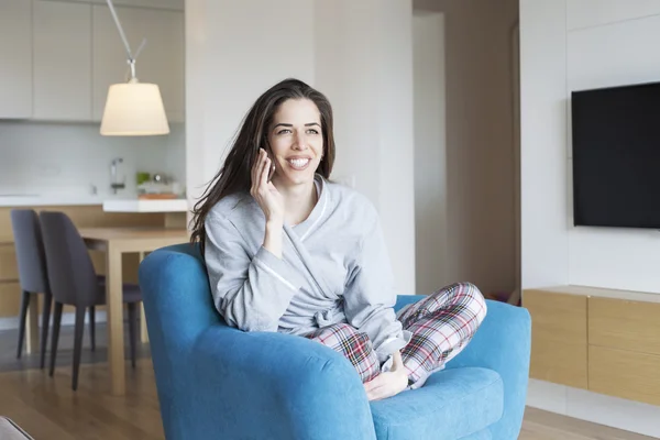 Vrouw in woonkamer met mobiele telefoon — Stockfoto