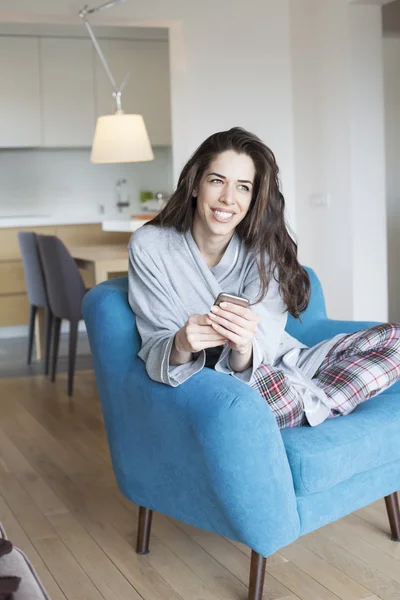 Vrouw in woonkamer met mobiele telefoon — Stockfoto