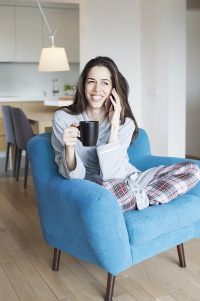 Mujer sentada en un sofá en el salón. Escena de la mañana, mujer sonriendo — Foto de Stock