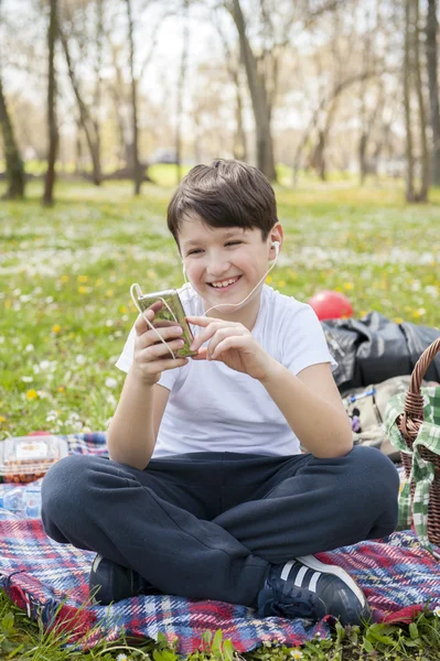 Boy listening to music in park — Stock Photo, Image