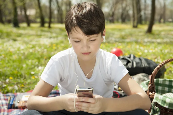 Boy listening to music in park — Stock Photo, Image